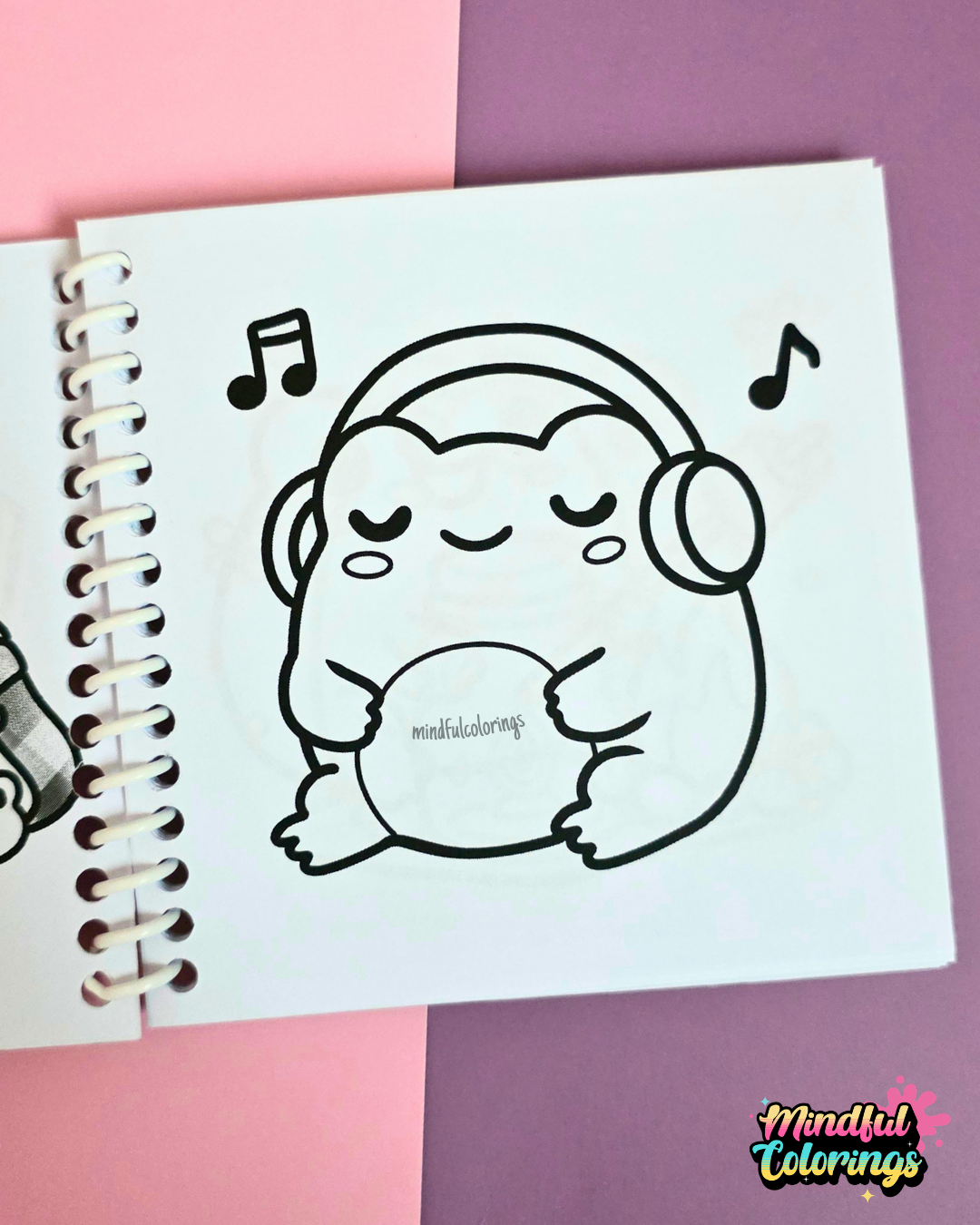 Mini frog-themed colouring book page featuring a peaceful frog wearing headphones while listening to music.