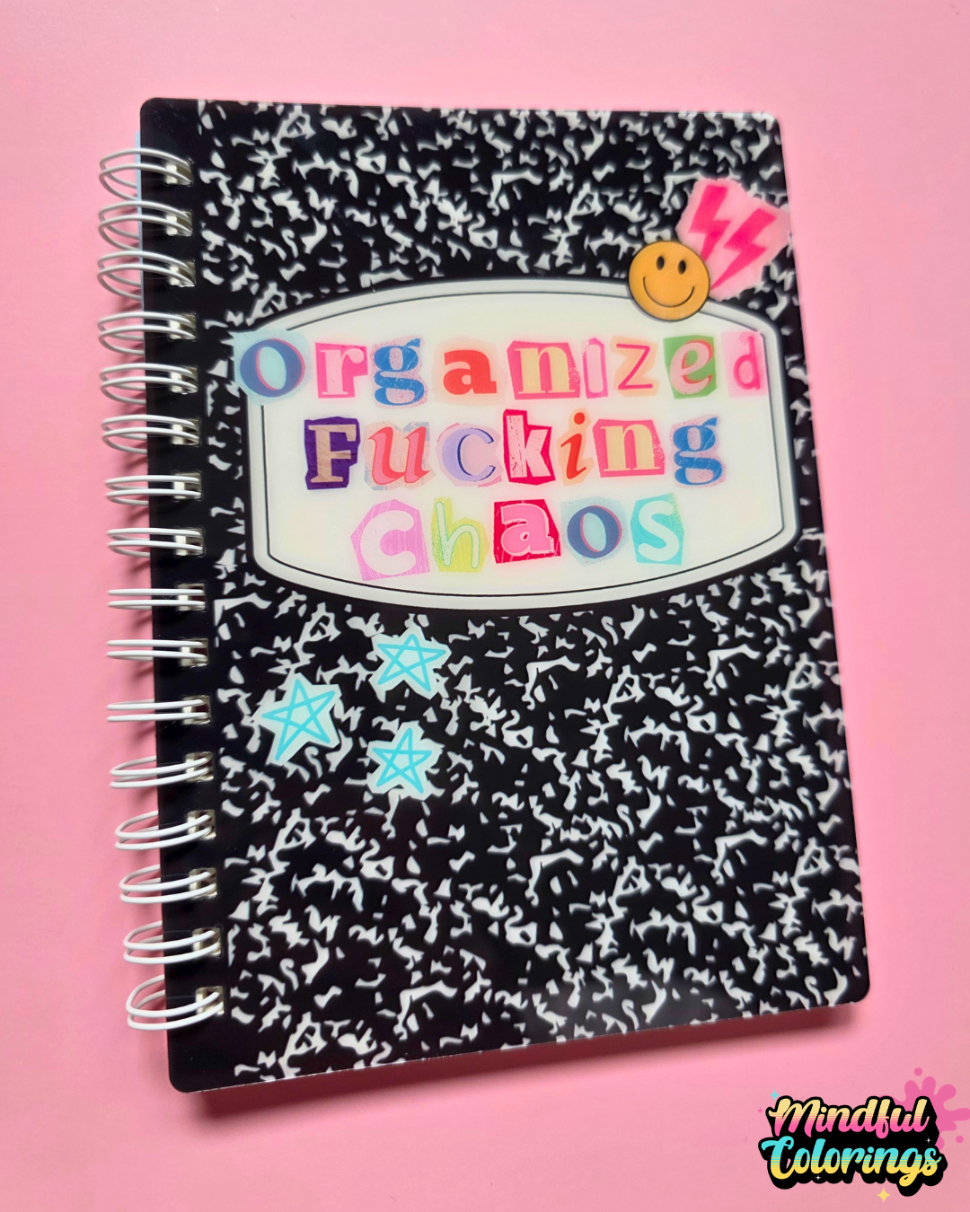 Notebook with colorful text that says "Organized Fucking Chaos" on a pink background