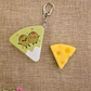 Cheese shaped fidget keychain with cartoon olives on the front
