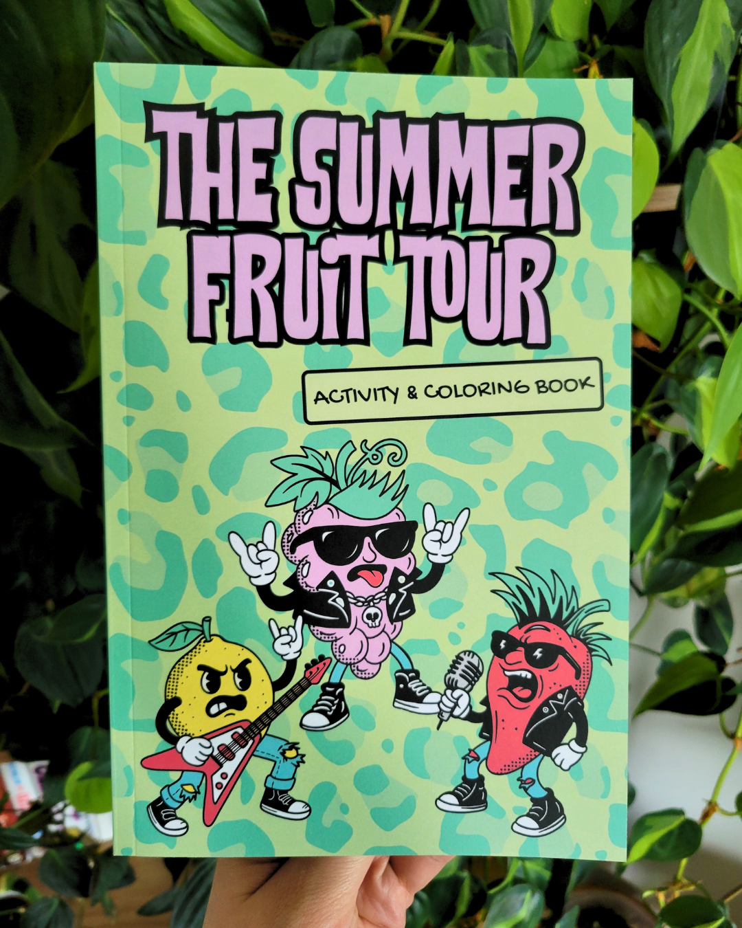 Coloring book titled 'The Summer Fruit Tour' with the words "activity & coloring book". Shows metalhead fruits on the cover playing instruments