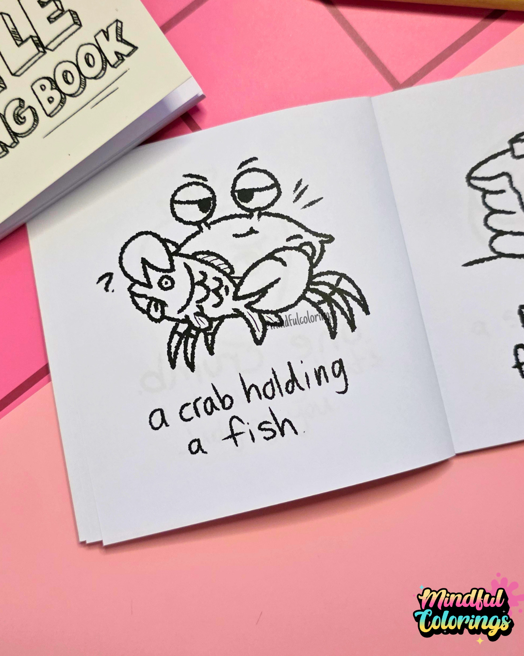 Mini colouring book page featuring a crab holding a fish with the caption "a crab holding a fish."