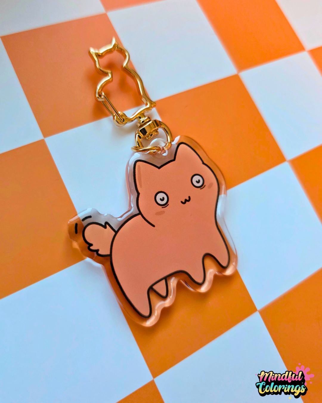 Acrylic keychain featuring a chubby orange cat  looking concerned with wide eyes attached to a gold cat-shaped clasp on an orange checkered background.