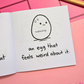 Mini coloring book with a cartoon egg and text that says "an egg that feels weird about it" on a pink surface
