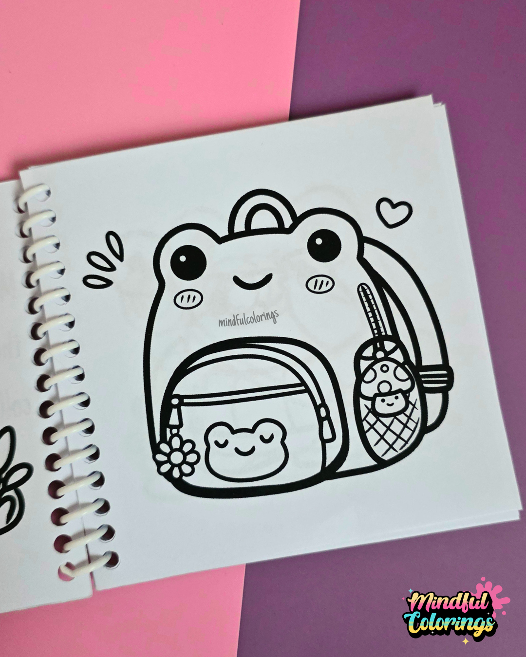 Mini frog-themed colouring book page featuring a cute frog-shaped backpack with a matching frog pouch, flower charm, and mushroom drink bottle.