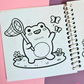 Mini frog-themed colouring book page featuring a happy frog holding a butterfly net while chasing butterflies in a grassy meadow with flowers.