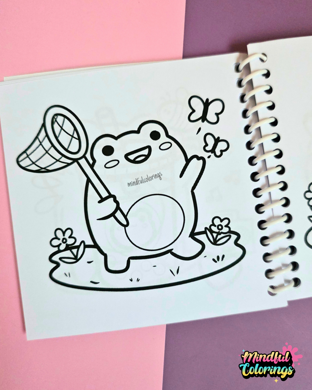 Mini frog-themed colouring book page featuring a happy frog holding a butterfly net while chasing butterflies in a grassy meadow with flowers.
