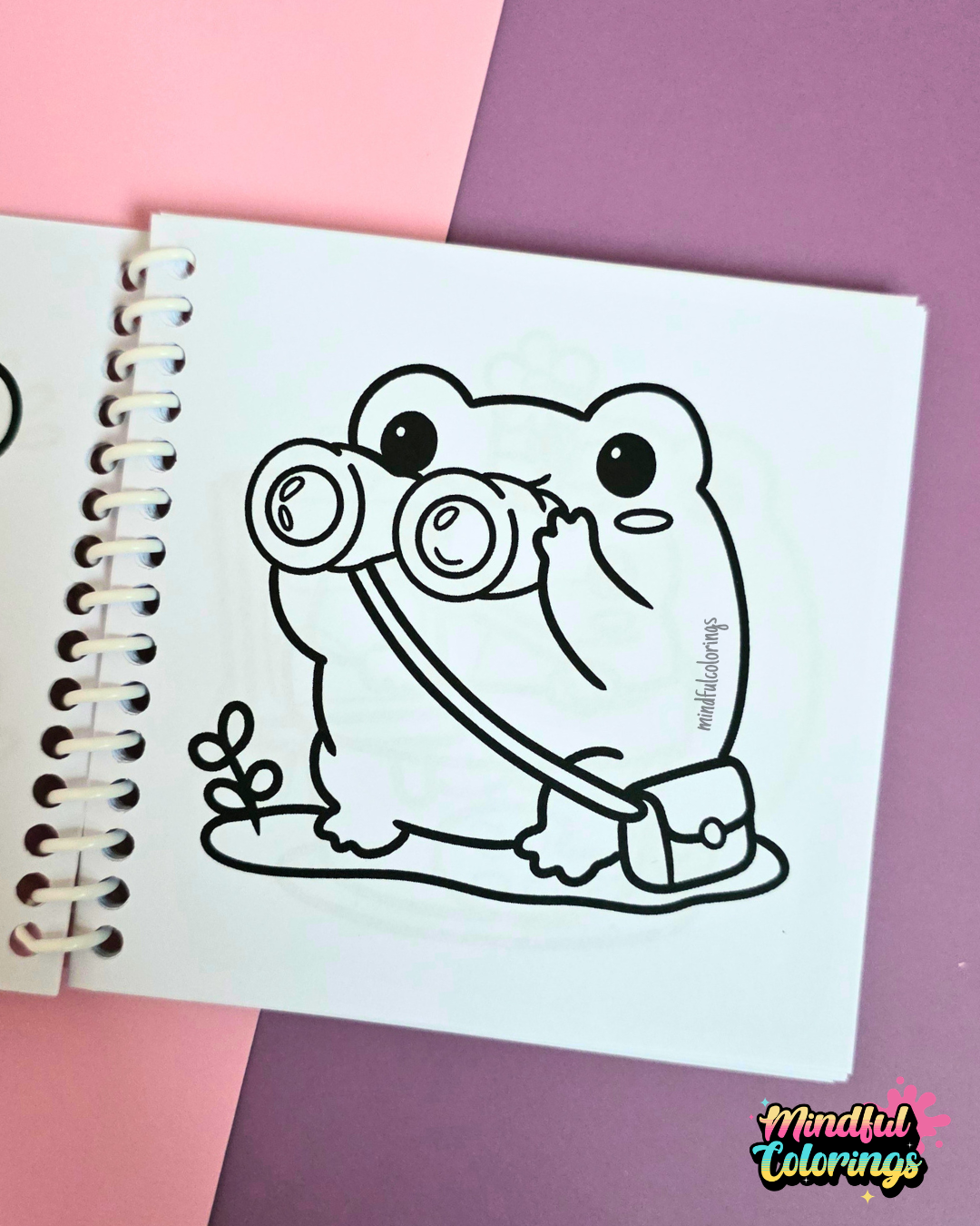 Mini frog-themed colouring book page featuring a curious frog looking through binoculars while carrying a small satchel.