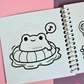 Mini frog-themed colouring book page featuring a happy frog floating in an inflatable swim ring while relaxing in the water and listening to music.