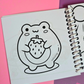 Mini frog-themed colouring book page featuring a cute frog holding a large strawberry.