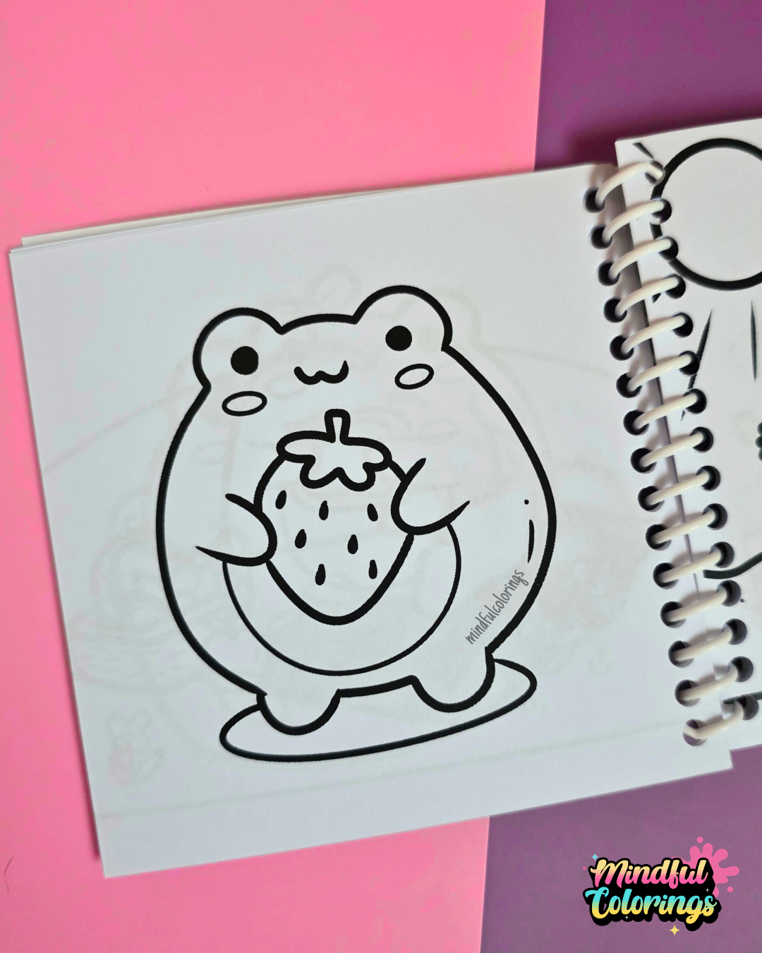 Mini frog-themed colouring book page featuring a cute frog holding a large strawberry.