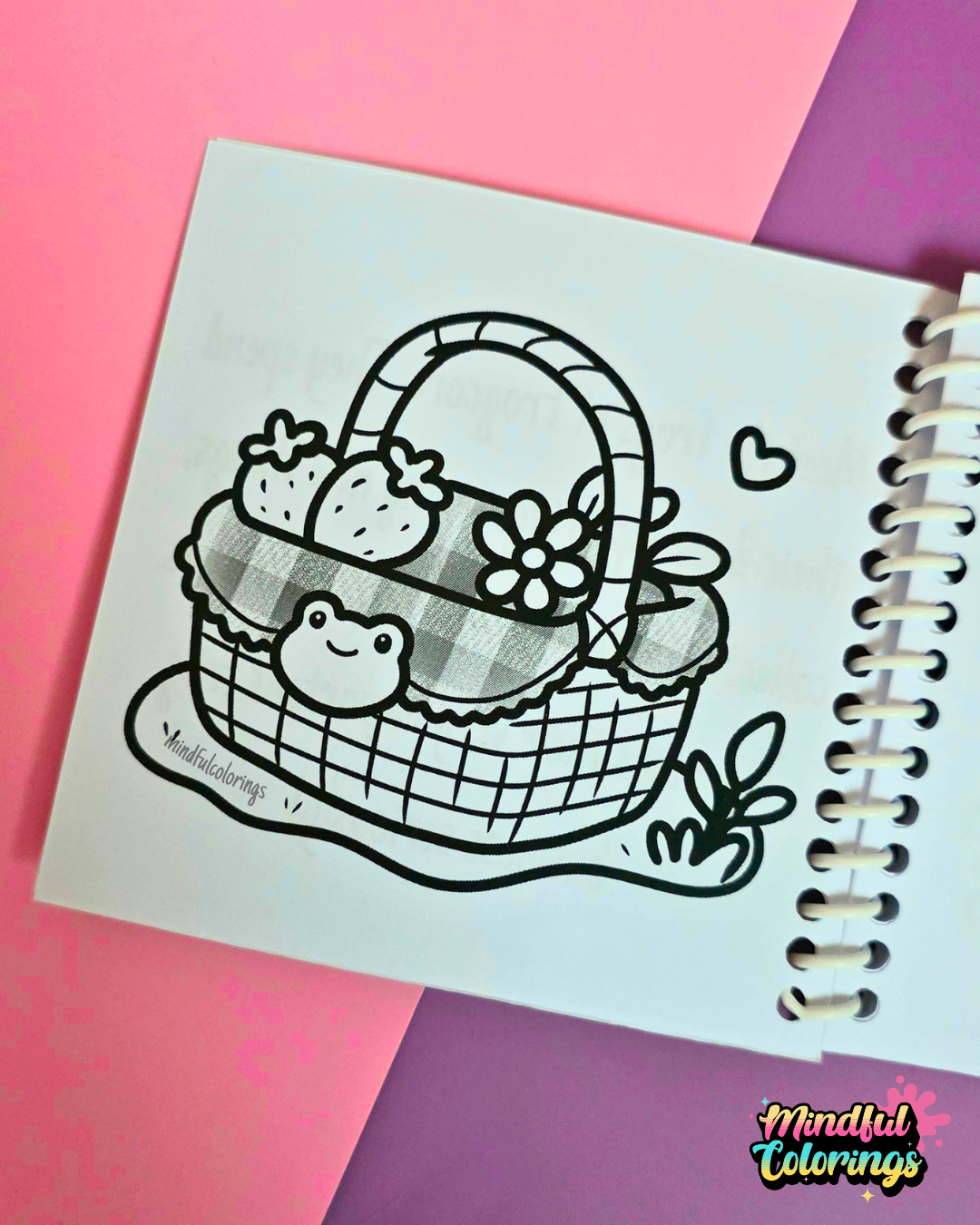 Mini frog-themed colouring book page featuring a picnic basket decorated with a frog face, filled with strawberries, flowers, and cozy frogcore details.