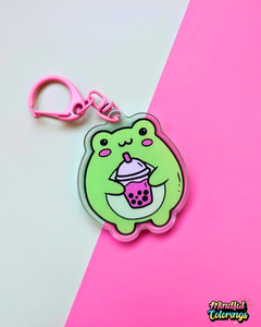 Acrylic keychain featuring a cute green frog holding a pink bubble tea drink on a pink and mint background.