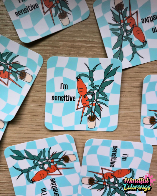 Stickers with the viral Marcus the Worm character hiding behind a green houseplant with the text "I'm Sensitive" with a blue checkered background