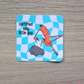 Sticker with the viral Marcus the Worm character crouched next to a rock with the text "Certified Silly Little Guy" with a blue checkered background