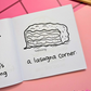 Mini coloring book with a lasagna illustration on a wooden surface