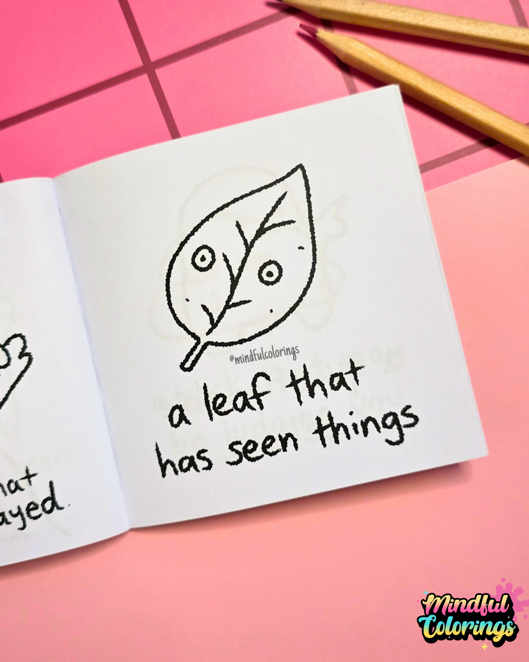 Mini coloring book with a leaf illustration and text  that says "a leaf with trust issues" on a pink surface