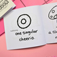Mini coloring book with a black and white illustration of a cheerio that says "a single cheerio" on a pink surface