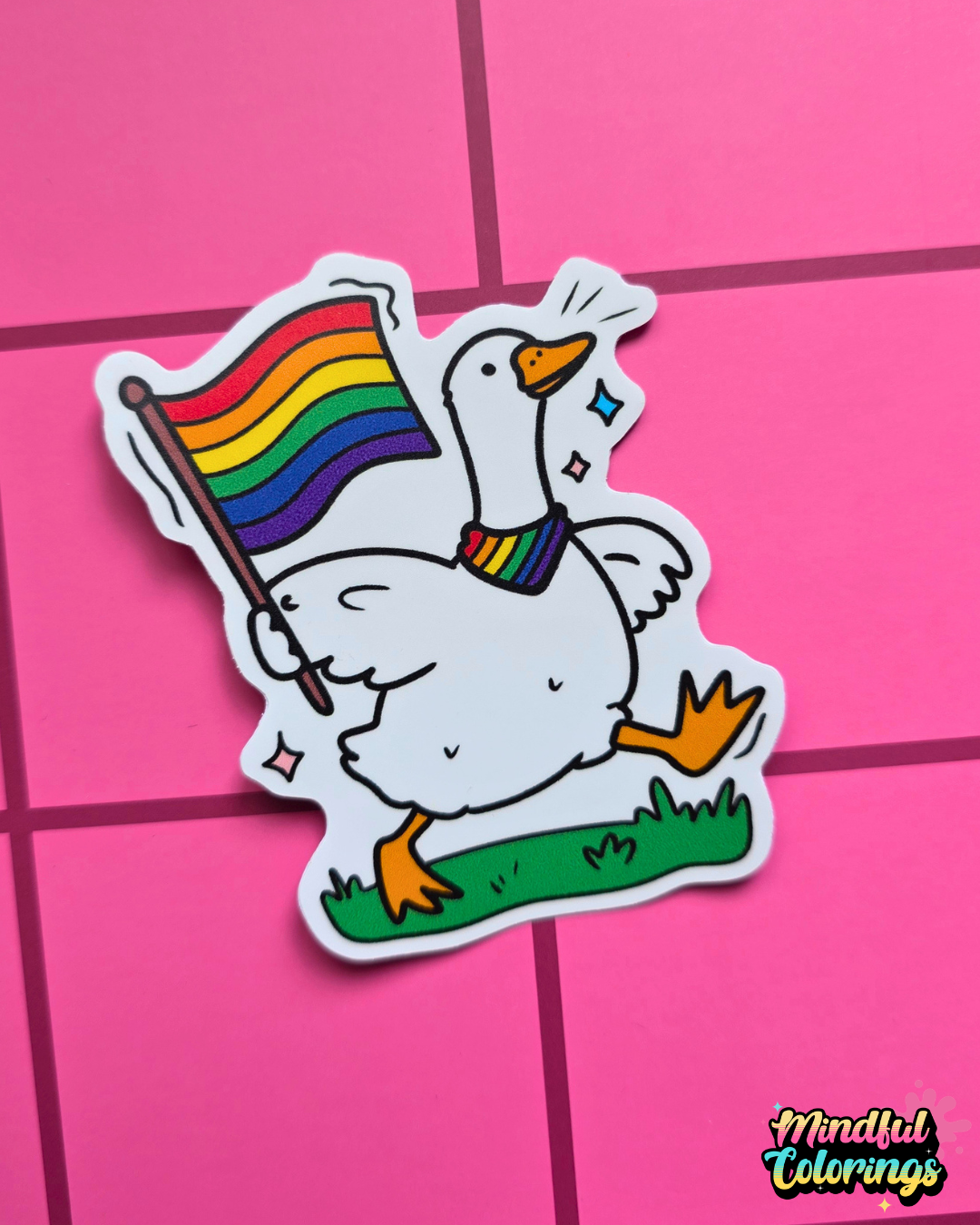Waterproof vinyl sticker featuring a happy goose waving a rainbow Pride flag while wearing a rainbow bandana on a pink checkered background.