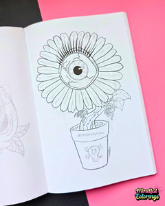 An open coloring book showing a black-and-white line art illustration of a flower with a large eye in the center, placed on a pink and black background. A 'Mindful Colorings' logo is visible in the bottom right corner.