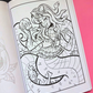 An open coloring book showing a black and white line art illustration of a Medusa with a skull on her head, placed on a bright pink background.