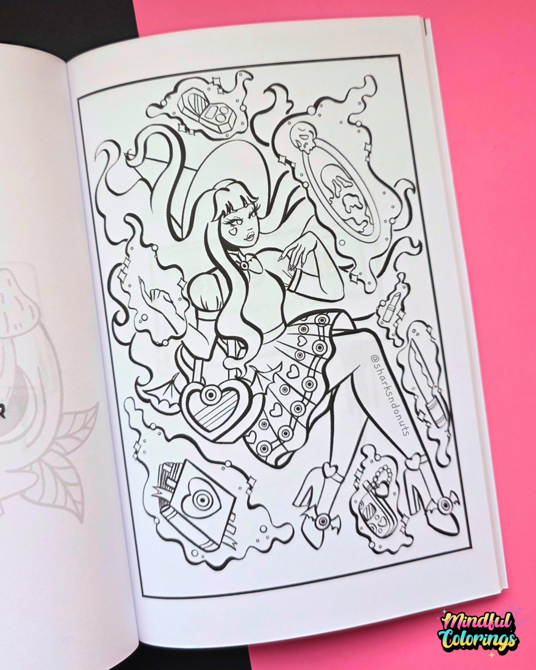 An open coloring book showing a black-and-white illustrated page with a Spooky Y2K  character and decorative elements, photographed against a bright pink background.