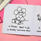 Mini coloring book with a flower character holding a briefcase labeled '$' with text that says "a flower about to do a shady business deal" on a pink surface